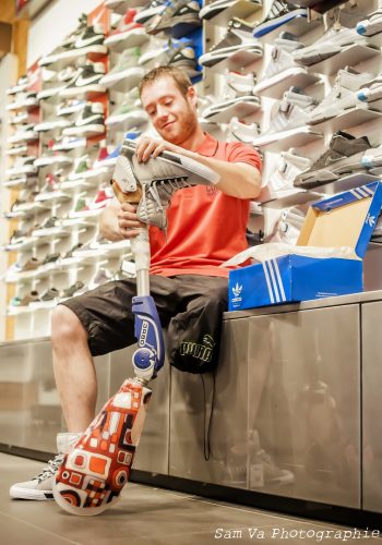 Un sportif dans un magasin de chaussure en train d'essyer une chaussure sur sa prothèse